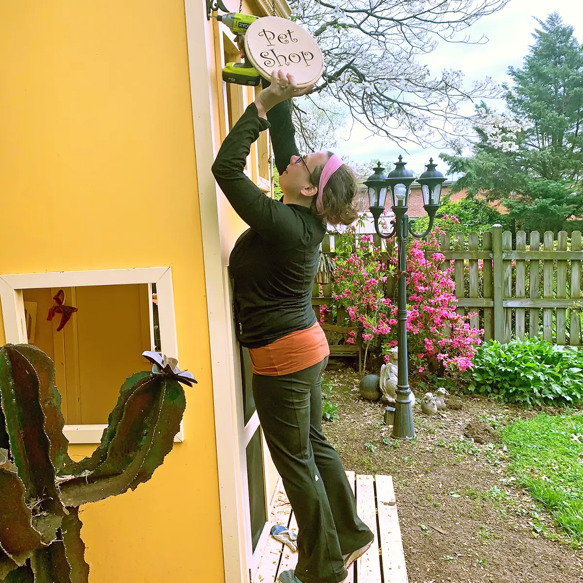Creator of Little Main Street attaching sign to playhouse